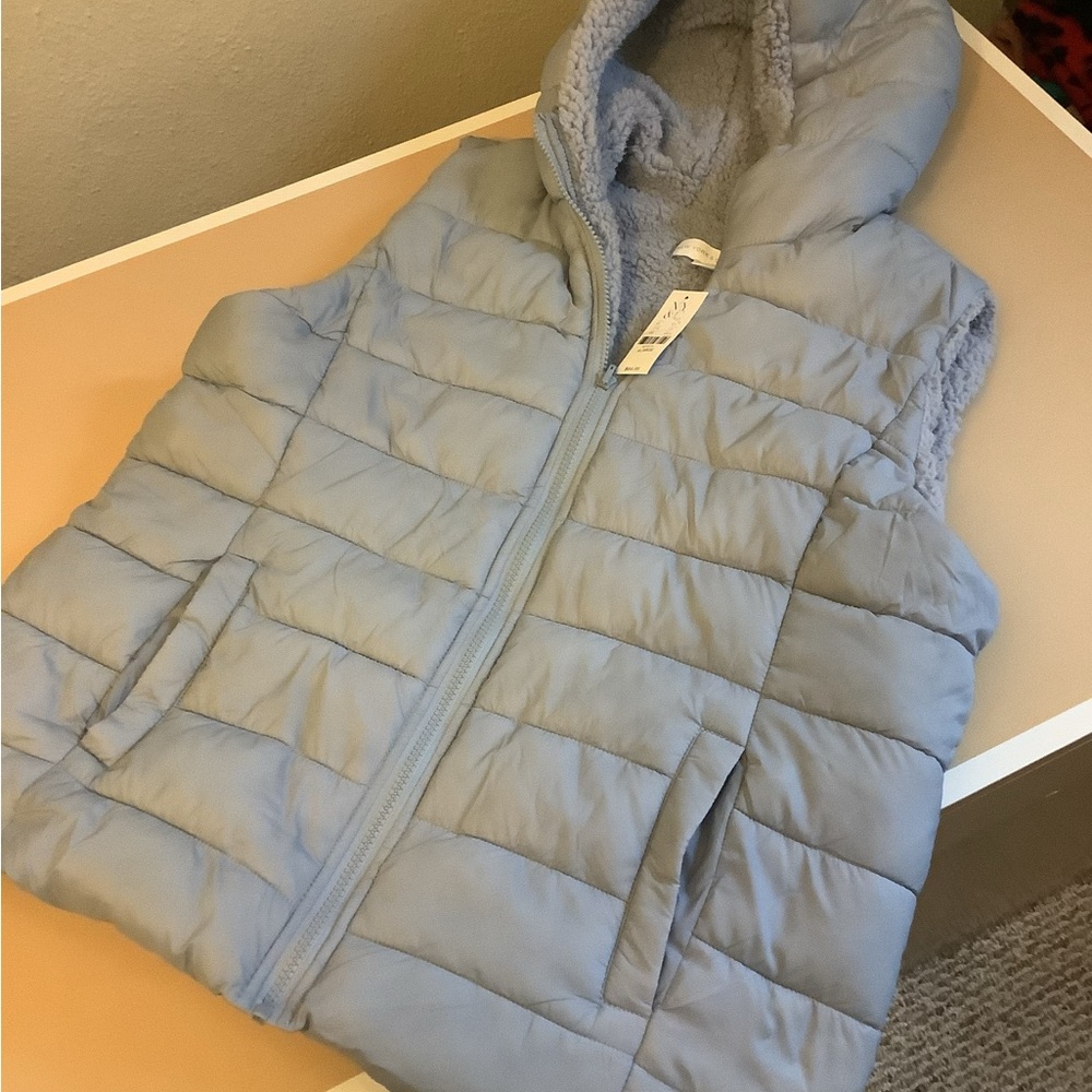 Light blue Women’s vest with pockets and a hood.